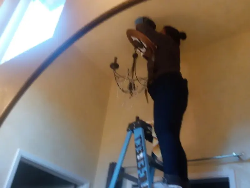 Electrician installing a chandelier in a Burton residence